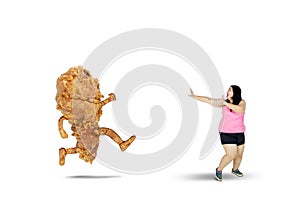 Obese woman running away from a fried chicken
