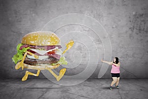Obese woman running away from a hamburger