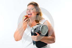 Obese woman with scale under arm and apple