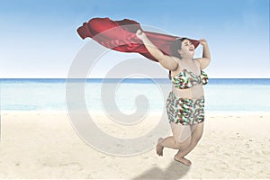 Obese woman with scarf runs on beach