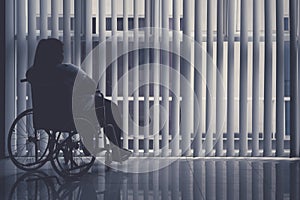 Obese woman sits in the wheelchair by the window