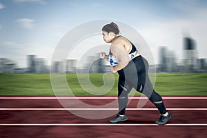 Obese woman sprinting exercises on the track