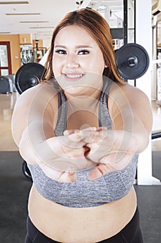 Obese woman stretching in the gym center