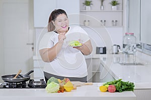 Obese woman tasting a bowl of healthy salad