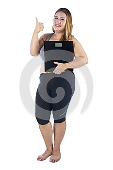 Obese woman with thumb up and weight scales