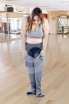 Obese woman trying to wear her old jeans