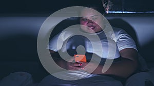 Obese woman using smart phone before sleep