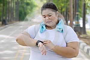 Obese woman wearing her smartwatch on the road