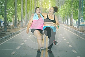 Obese women dancing and laughing together at park