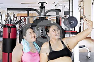 Obese women with smartphone in gym center