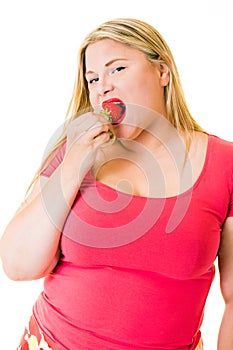 Obese young blond woman eating ripe strawberry
