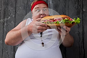 Obese young man encroaches on a big sandwich