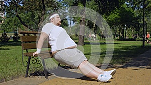 Obese young man exercising on bench, outdoor workouts, struggle to slim down