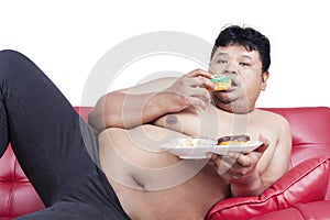 Obesity person eating donuts on sofa