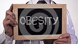 Obesity written on blackboard in doctor hands, healthy nutrition recommendations