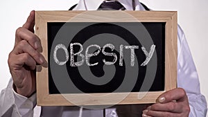 Obesity written on blackboard in doctor hands, healthy nutrition recommendations photo
