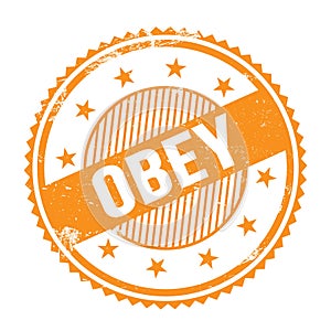 OBEY text written on orange grungy round stamp