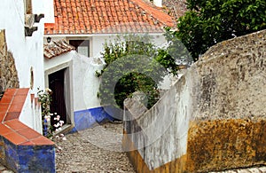 Beautiful tiny cobblestoned street, walls, and roofs in Obidos, Portugal photo