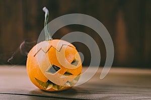 Closeup Photo of Small Carved Pumpkin on the dark Wooden Background photo