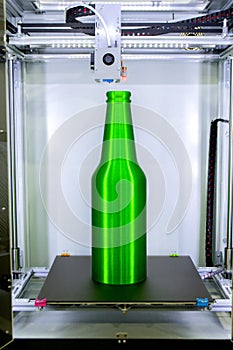 Object green bottle printed on 3D printer close-up, inside on 3d printer.
