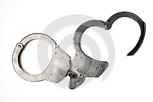 Object is a unilateral handcuff made of iron, single lock, on a white background, symbolizing the law and the offense.