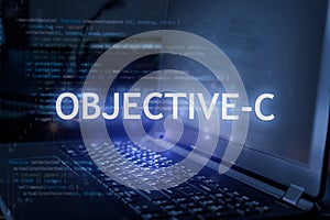 Objective-C inscription against laptop and code background. Learn programming language, computer courses, training