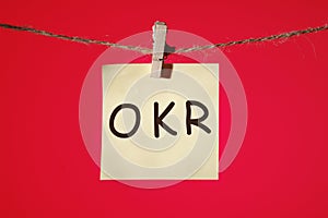 Objectives, Key and Results. OKR text on a yellow sticker on a red background