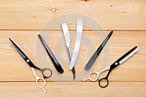 Objects for cutting hair and beard, razors and scissors, comb, lie on a light wooden background.