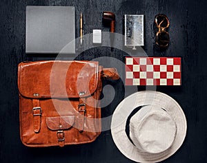 Objects in touristic set ready for a holiday. Leather travel bag, flask, notebook, smoking pipe.