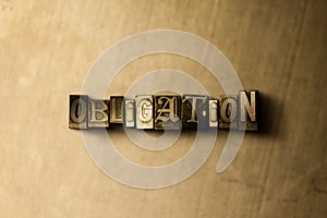OBLIGATION - close-up of grungy vintage typeset word on metal backdrop
