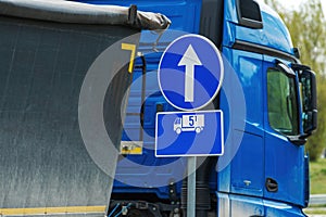 Obligatory direction traffic sign for heavy truck vehicles over five tons, european blue circle signage with white arrow photo