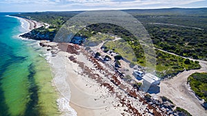 Oblique Landscape aerial view of 4WD and modern caravan parked adjacent to a sparkling sunny beach