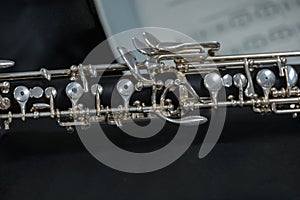 Oboe musical instrument resting on a score The oboe has a black body with silver keys, made of grenadilla wood
