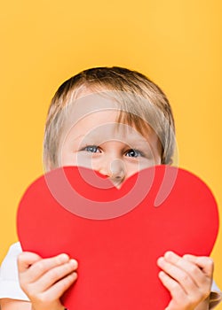 obscured view of boy covering face with red paper heart photo