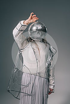 obscured view of stylish woman covering face with disco ball