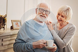 Observant wife bringing some hot tea for her smiling man