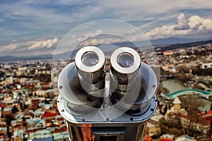 Observation deck and viewing binoculars close-up overlooking the city of Tbilisi.