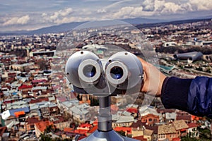 Observation deck and viewing binoculars close-up overlooking the city of Tbilisi.