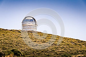 Observatory on a mountain. Large telescope dome. Gran Telescopio Canarias. Dark sky site in the mountains of La Palma. Blue sky.