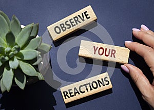 Observe your Reactions symbol. Concept word Lets do this on wooden blocks. Businessman hand. Beautiful deep blue background with