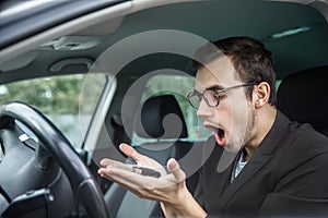 Obsessed young guy is lokking at the keys. He is holding the keys in his hands. His mouth is wide open