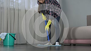 Obsessive with cleanliness young lady thoroughly washing floor of her house