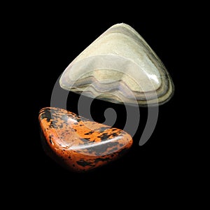 Two obsidian tumbling stones on black background