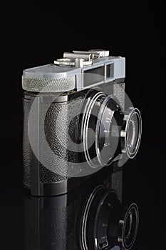 Obsolete film camera isolated on the dark background with reflection