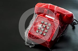 Obsolete technology and abandoned telephone concept with a vintage phone covered in spider webs isolated on black background with