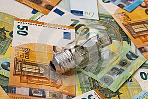 Obsolete uneconomical and unecological bulb on euro banknotes photo