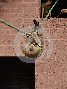 Obstacle, soldier and training with rope climbing for fitness, exercise or challenge outdoor with gear. Military, people