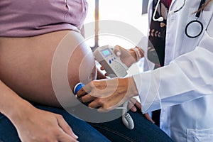 Obstetrician gynecologist performing Doppler auscultation checking blood flow in placenta and uterus in the clinic