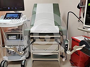 Obstetrics table in gynecological clinic with stirrups next to ultrasound machine photo