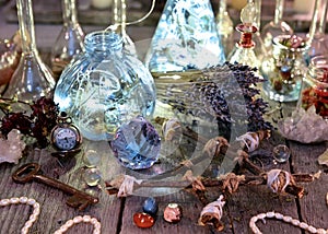 Magic bottles with lights, pentagram, crystal and ritual objects on witch table